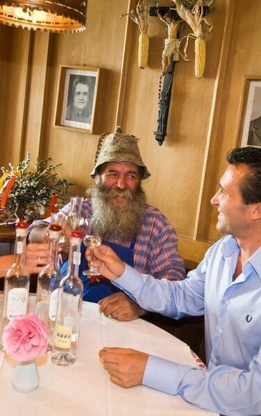 3 persone a un tavolo che brindano con un bicchiere di grappa | © Hotel Gassenwirt - Kiens