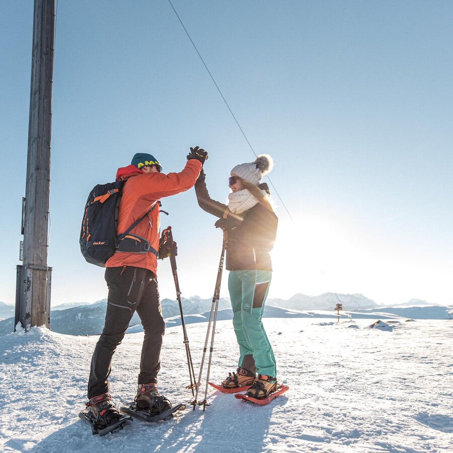 Gli escursionisti con le racchette da neve si danno il cinque in cima alla vetta innevata