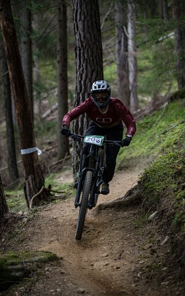 Eine Person fährt mit einem Mountainbike auf einem schmalen Pfad durch den Wald. | © Stromberg - Enduro Tirol