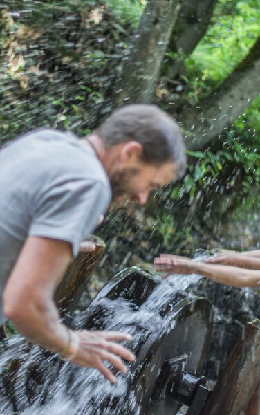 Eine Familie beim Spielen mit Wasser im Wald im Sommer. | © TV Antholzertal
