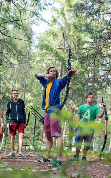 Eine Gruppe junger Leute beim Bogenschießen im Wald. | © Alex Filz