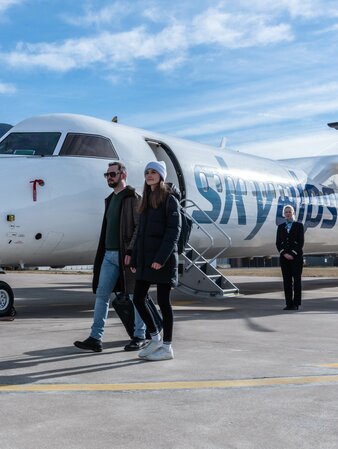 Ein Mann und eine Frau steigen vom Skyalps Flugzeug aus. | © Skirama Kronplatz