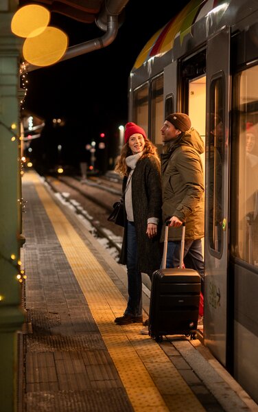 Lächelnd steigt ein Paar aus der Zuglinie aus.
