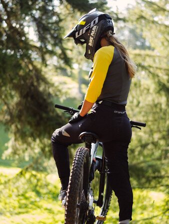 Eine Mountainbikerin steht mit ihrem Rad auf einem kleinen Pfad im Wald. | © Daniel Niederkofler