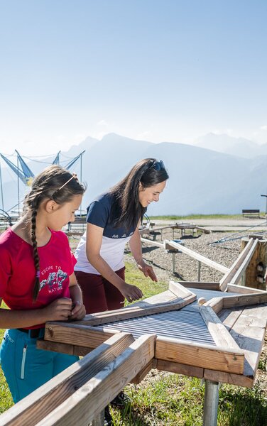 Eltern mit ihren beiden Töchtern bei der Holzkugelbahn am Kronplatz-Gipfel im Sommer. | © Harald Wisthaler