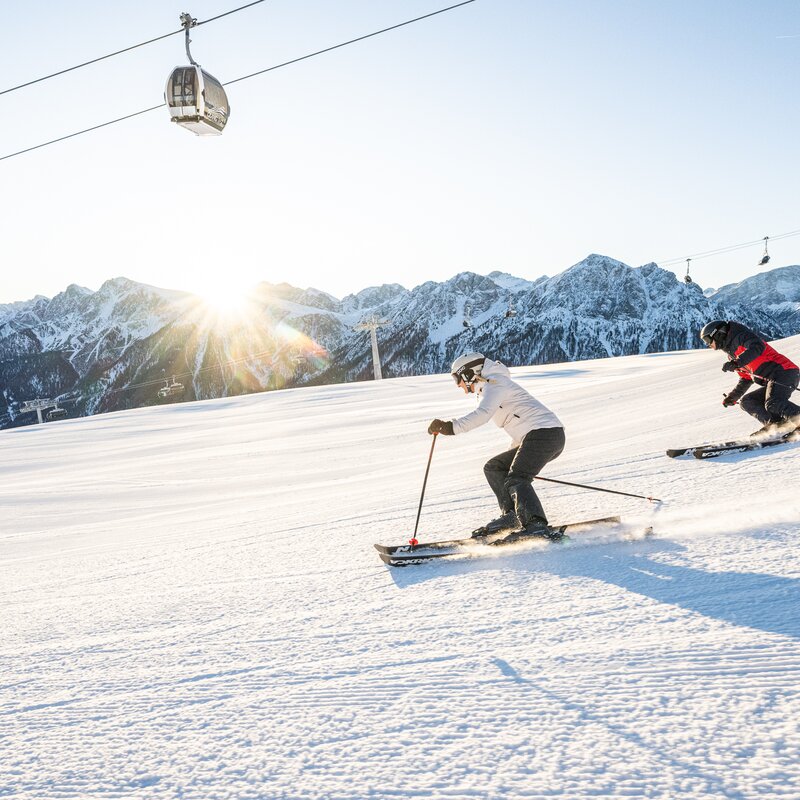 Perfekt präparierte Pisten werden von 2 Skifahrern früh morgens befahren, im Hintergrund die Kabinenbahn. | © Harald Wisthaler